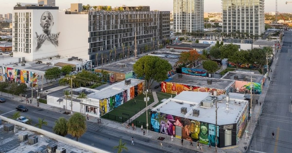 Wynwood Miami with colorful mural-covered warehouses and modern residential buildings rising behind them